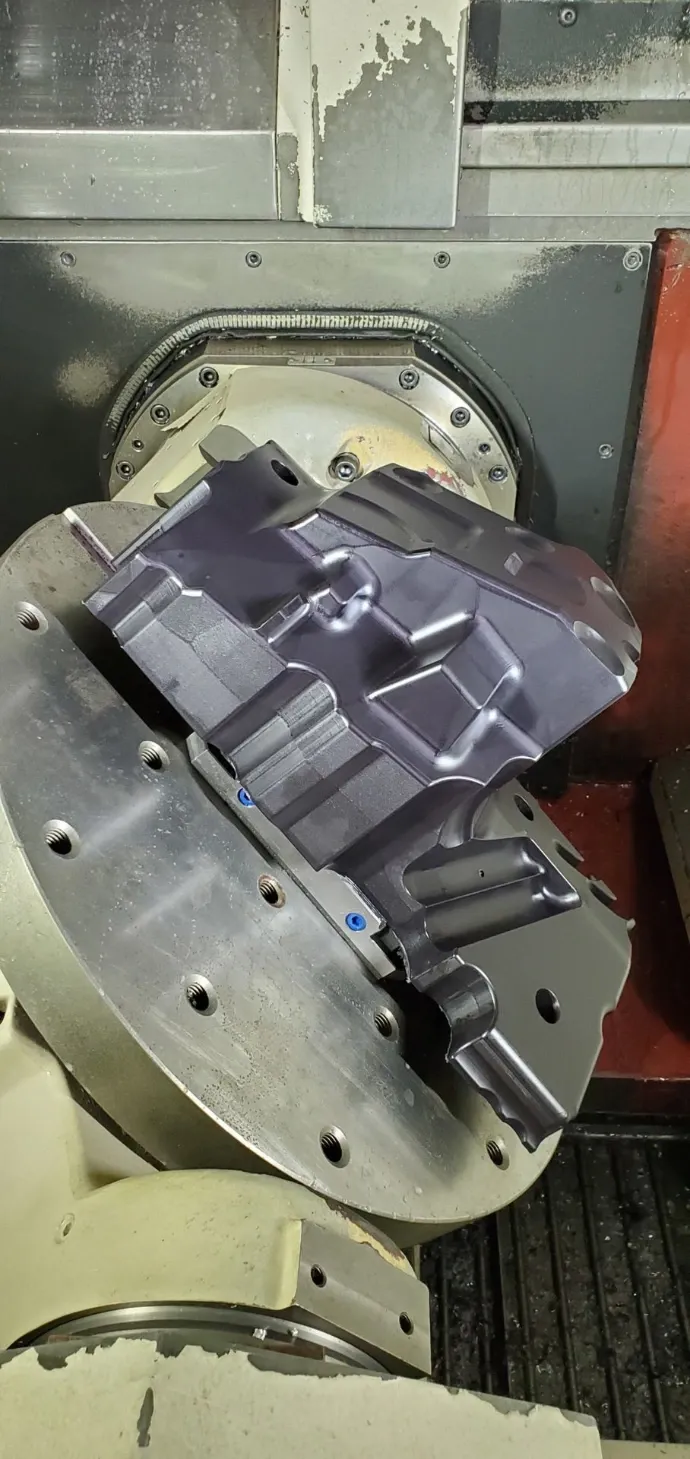 Large aerospace component mounted on a rotary table inside a five-axis machining centre.